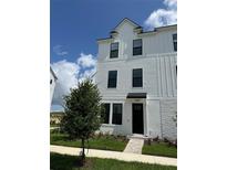 Charming three-story townhome with a modern white facade and a well-manicured front lawn at 15107 Grove Lake Dr, Winter Garden, FL 34787