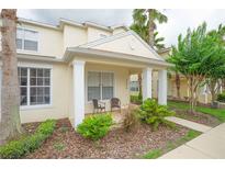 Charming townhouse with a covered front porch, lush landscaping, and two outdoor chairs at 17516 Blessing Dr, Clermont, FL 34714