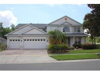 Stunning two-story home with a three-car garage, paver driveway, manicured lawn, and lush landscaping at 2543 Chapala Dr, Kissimmee, FL 34746