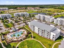 Stunning aerial view of a community with a resort-style pool, lush landscaping, and modern apartment buildings near a lake at 3180 Paradox Cir # 304, Kissimmee, FL 34746