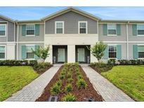 Charming townhome featuring a landscaped walkway leading to the front door with teal shutters and gray siding at 720 Gardenia Ln, Davenport, FL 33897