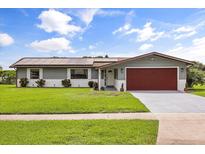 Charming single-story home with a well-manicured lawn, solar panels, and an attached two-car garage at 930 Chickadee Dr, Port Orange, FL 32127
