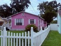 Charming pink home with a white picket fence and well-manicured lawn and mature trees at 1038 26Th St, Orlando, FL 32805