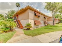 Inviting two-story condo featuring shuttered windows, manicured lawn, mature trees, and a cozy staircase to the entrance at 150 Wax Myrtle Woods Ct # 3D, Deltona, FL 32725