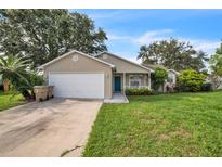 Charming single-story home featuring a manicured lawn, attached garage, and inviting blue front door at 1840 Orange View Ct, Kissimmee, FL 34746