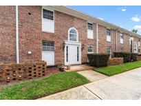 Charming brick townhouse featuring a white front door, manicured bushes, and lush green grass at 4312 Lake Underhill Rd # 19-B, Orlando, FL 32803