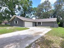 Charming single-story home with a gray exterior, attached garage, and a long driveway at 4883 Cherokee Rose Dr, Orlando, FL 32808