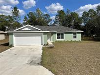 Charming single-story home with a well-maintained lawn and an attached two-car garage at 51 Fir Dr, Ocala, FL 34472