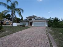 Charming single-story home with a brick driveway, two-car garage, and lush landscaping at 6569 Long Breeze N Rd, Orlando, FL 32810