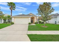 Charming single-story home with a well-maintained lawn, palm tree, and two-car garage at 915 Lockbreeze Dr, Davenport, FL 33897