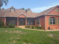 Charming single-story home with a screened-in porch, lush lawn, and colorful exterior paint scheme at 1031 Kings Hwy, Kissimmee, FL 34744