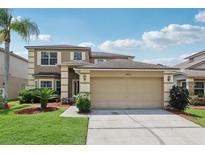 Inviting two-story home featuring a manicured lawn, attached two-car garage, and desert landscaping at 14680 Yorkshire Run Dr, Orlando, FL 32828