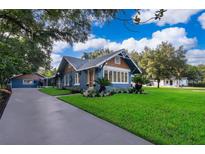 Charming home with a blue exterior, well-manicured lawn, and a long driveway leading to a detached garage at 1505 Delaney Ave, Orlando, FL 32806