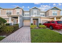 Charming townhome featuring a one-car garage, brick pathway, and well-maintained front lawn at 16449 Cedar Crest Dr, Orlando, FL 32828
