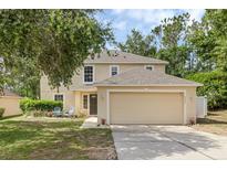 Two-story home with a two-car garage, well-maintained lawn, and inviting front entrance at 2255 Tealwood Cir, Tavares, FL 32778