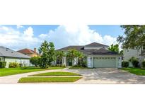 Charming one-story home with a lush green lawn, mature trees, and a two car garage at 2406 Blossomwood Dr, Oviedo, FL 32765