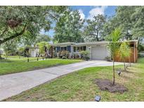 Charming single-story home featuring a well-manicured lawn, complemented by mature trees and a concrete driveway at 2910 Hargill Dr, Orlando, FL 32806