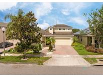 Charming home features a well-manicured lawn, brick driveway, and inviting facade at 7214 Tattant Blvd, Windermere, FL 34786