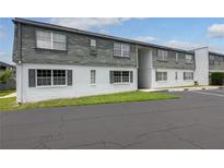 Two-story condo featuring a gray shingled roof, white siding, and reserved parking spaces at 1000 S Semoran Blvd # 604, Winter Park, FL 32792