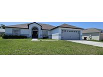 Charming one-story home featuring a gray roof, attached garage, and well-maintained front yard at 1930 Dolphin Drive, Kissimmee, FL 34759