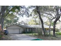 Charming single-story home with a two-car garage, surrounded by mature trees and lush landscaping at 220 Morton Ln, Winter Springs, FL 32708