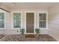 Inviting front entrance featuring a welcoming welcome mat, potted plants, sidelight windows and neutral earth tone colors at 2704 Lobelia Dr, Lake Mary, FL 32746