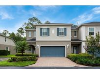 Charming two-story townhome with a brick driveway, blue shutters and a well-manicured lawn at 411 Evening Sky Dr, Oviedo, FL 32765
