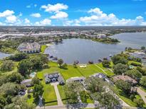 An aerial view of a luxury waterfront property with a spacious lawn and private dock on a sunny day at 49 Interlaken Rd, Orlando, FL 32804
