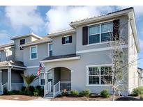 Charming townhome showcasing a well-maintained lawn, neutral gray exterior, shutters, and covered porch with the U.S. flag at 4984 Windermere Ave, Kissimmee, FL 34746