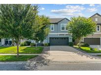 Charming two-story home with a well-manicured lawn and a two-car garage is bathed in natural light against a blue sky at 672 Seven Oaks Blvd, Winter Springs, FL 32708