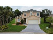 Inviting two-story home with well-manicured lawn and attached two car garage on a sunny day at 831 Corvina Dr, Davenport, FL 33897
