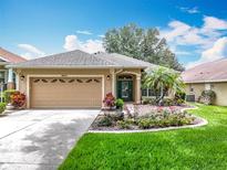 Charming home featuring a lush lawn, a well-maintained garden, and a two-car garage at 16631 Champions Ct, Clermont, FL 34711