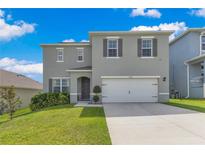 Two-story home features a two-car garage, manicured lawn, and neutral-tone stucco at 1854 Juneberry St, Clermont, FL 34715