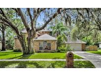 Charming brick home with lush lawn, mature trees, and well-maintained landscaping at 5430 Baytowne Pl, Oviedo, FL 32765