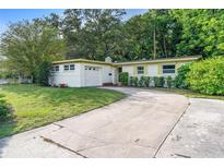 Charming single-story home features a manicured lawn, long driveway, and attached one-car garage at 5815 Holmes Dr, Orlando, FL 32808