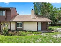 Charming townhome featuring a front door, beige exterior, chimney, and well-maintained lawn at 6809 Magnolia Pointe Cir, Orlando, FL 32810