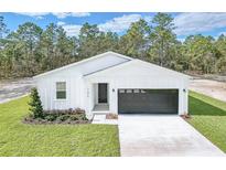 Charming one story home with white siding, black garage door, and a well manicured lawn at 7520 Sw 134Th Ave, Dunnellon, FL 34432