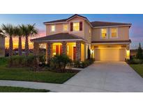 Inviting two-story home with a two-car garage and well-manicured landscaping at sunset at 4111 Oaktree Dr, Davenport, FL 33837