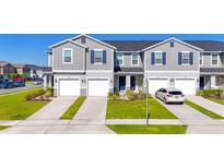 Modern townhouse exterior featuring gray siding, blue shutters, and attached garages at 1471 Mirabella Cir, Davenport, FL 33897