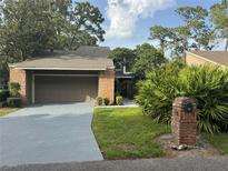 Charming brick home with a well-manicured front yard, mature trees, and a two-car garage at 200 Hummingbird Ln, Longwood, FL 32779