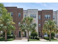Charming multi-story townhomes with brick and white brick exteriors, complemented by lush landscaping and palm trees at 464 W Plant St, Winter Garden, FL 34787