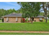 Charming single-story brick home with a well-manicured lawn and mature landscaping at 5929 Hatteras Dr, Port Orange, FL 32127