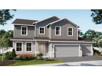 Charming two-story home featuring a two-car garage, gray siding, and beautifully landscaped front yard at 679 Birsdwill Ln, Deland, FL 32720