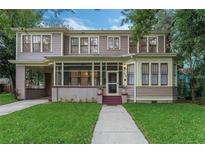 Charming two-story home featuring a screened front porch, classic architectural details, and lush green lawn at 803 E Hardwood St, Orlando, FL 32803
