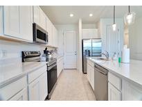 Well-lit kitchen featuring white cabinets, stainless steel appliances, and a light speckled countertop at 832 Longboat Dr, Davenport, FL 33896