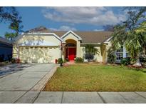 Inviting single-story home with a well-manicured lawn, mature landscaping, and a vibrant red front door at 1662 Canoe Creek Rd, Oviedo, FL 32766