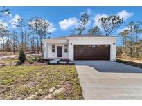 Charming single-story home with a well-manicured lawn, a dark brown garage door and inviting front entrance at 23430 Sw Neptune Blvd, Dunnellon, FL 34431