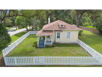 Charming home with a white picket fence and front porch surrounded by lush greenery at 244 N Leavitt Ave, Orange City, FL 32763