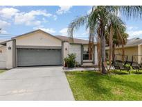 Charming single Gathering home featuring an attached garage, palm tree and landscaped yard at 3280 Pinto Dr, Kissimmee, FL 34746