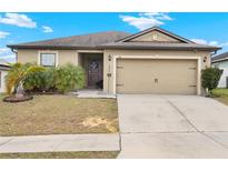 Charming single-story home featuring an attached two-car garage and well-maintained landscaping at 411 Ridges Dr, Dundee, FL 33838